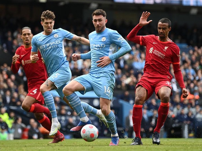 MANCHESTER, ENGLAND - APRIL 10: Aymeric Laporte of Manchester City shoots whilst under pressure from Joel Matip of Liverpool during the Premier League match between Manchester City and Liverpool at Etihad Stadium on April 10, 2022 in Manchester, England. (Photo by Shaun Botterill/Getty Images)