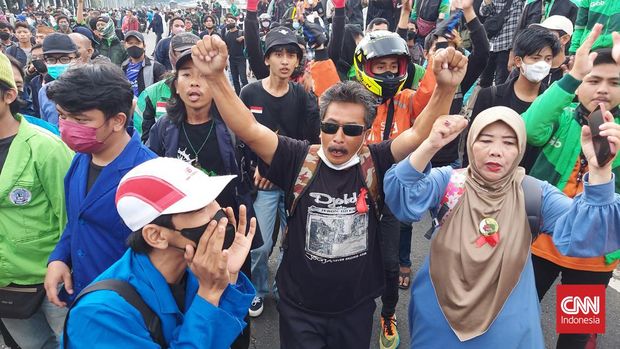 Puluhan massa aksi berpakaian ojek online (ojol) meneriakkan revolusi hingga turunkan Jokowi di depan kompleks parlemen DPR/MPR, Senayan, Jakarta, Senin (11/4). Mereka bergabung dengan aksi unjuk rasa oleh Badan Eksekutif Mahasiswa Seluruh Indonesia (BEM SI) yang membawa tuntutan menolak perpanjangan masa jabatan presiden.  CNN Indonesia/ Thohirin