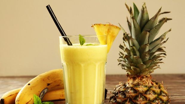 Fresh exotic smoothie with fruits and coconut milk on yellow background. Copy space.