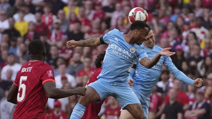 Manchester Citys Raheem Sterling, left, and Manchester Citys Phil Foden jump for the ball during the English FA Cup semifinal soccer match between Manchester City and Liverpool at Wembley stadium in London, Saturday, April 16, 2022. (AP Photo/Frank Augstein)