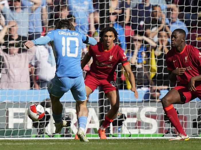 Manchester Citys Jack Grealish, left, scores his sides opening goal during the English FA Cup semifinal soccer match between Manchester City and Liverpool at Wembley stadium in London, Saturday, April 16, 2022. (AP Photo/Frank Augstein)