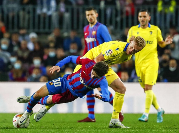 Barcelona's Gavi, left, vies for the ball with Cadiz's Jens Jonsson during a Spanish La Liga soccer match between FC Barcelona and Cadiz at the Camp Nou stadium in Barcelona, Spain, Monday, April 18, 2022. (AP Photo/Joan Monfort)