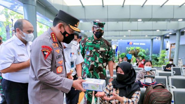 Kapolri Jenderal Listyo Sigit Prabowo membagikan masker ke penumpang di Stasiun Pasar Senen, Rabu (20/4/2022).