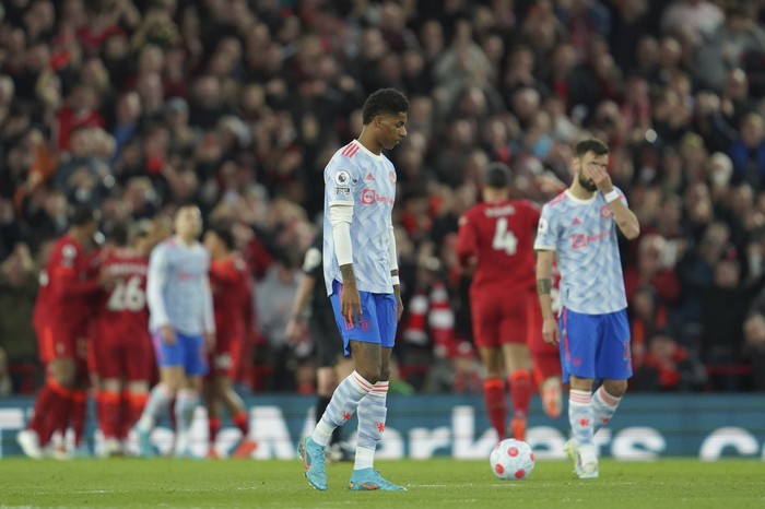 Manchester Uniteds Marcus Rashford, left, and Manchester Uniteds Bruno Fernandes, right, gesture as Liverpools Mohamed Salah celebrates with his teammates after scoring his sides second goal during the English Premier League soccer match between Liverpool and Manchester United at Anfield stadium in Liverpool, England, Tuesday, April 19, 2022. (AP Photo/Jon Super)