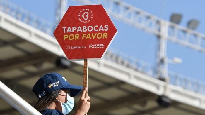 BARRANQUILLA, COLOMBIA - JANUARY 28: A civic volunteer holds a sing requesting the use of facemasks beforea match between Colombia and Peru as part of FIFA World Cup Qatar 2022 Qualifiers at Roberto Melendez Metropolitan Stadium on January 28, 2022 in Barranquilla, Colombia. (Photo by Gabriel Aponte/Getty Images)