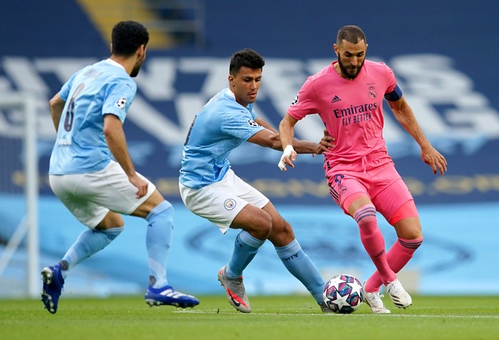MANCHESTER, ENGLAND - AUGUST 07: Karim Benzema of Real Madrid is challenged by Rodrigo of Manchester City during the UEFA Champions League round of 16 second leg match between Manchester City and Real Madrid at Etihad Stadium on August 07, 2020 in Manchester, England. (Photo by Dave Thompson/Pool via Getty Images)