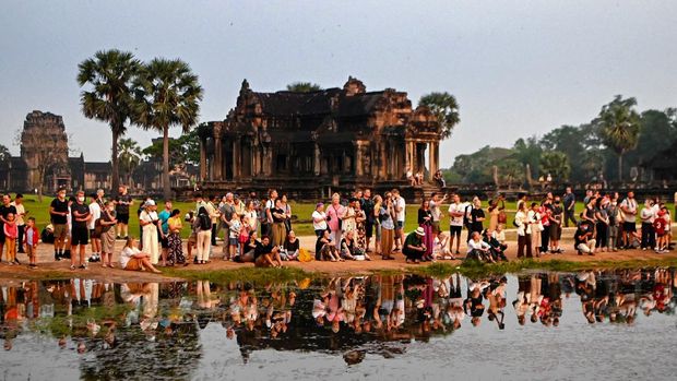 This picture taken on April 8, 2022 shows tourists gathering to watch the sun rise over the Angkor Wat temple complex, a UNESCO World Heritage Site, in Siem Reap province. (Photo by TANG CHHIN Sothy / AFP) / TO GO WITH Cambodia-economy-tourism, FOCUS by Suy SE