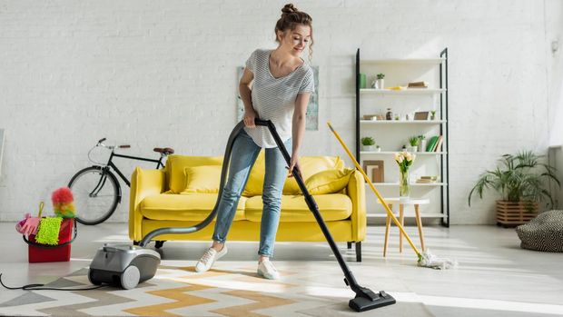 happy girl cleaning carpet with vacuum cleaner