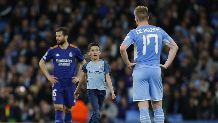 Soccer Football - Champions League - Semi Final - First Leg - Manchester City v Real Madrid - Etihad Stadium, Manchester, Britain - April 26, 2022 A young pitch invader runs to Manchester Citys Kevin De Bruyne during the match REUTERS/Craig Brough