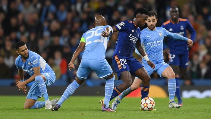 MANCHESTER, ENGLAND - APRIL 26: Vinicius Junior of Real Madrid is challenged by Fernandinho and Bernardo Silva of Manchester City during the UEFA Champions League Semi Final Leg One match between Manchester City and Real Madrid at Etihad Stadium on April 26, 2022 in Manchester, England. (Photo by David Ramos/Getty Images)