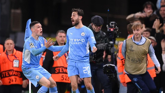 MANCHESTER, ENGLAND - APRIL 26: Bernardo Silva of Manchester City celebrates with teammate Phil Foden after scoring their sides fourth goal during the UEFA Champions League Semi Final Leg One match between Manchester City and Real Madrid at Etihad Stadium on April 26, 2022 in Manchester, England. (Photo by Laurence Griffiths/Getty Images)