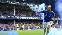 Richarlison memungut petasan biru usai mencetak gol semata wayang dalam kemenangan Everton atas Chelsea. Foto: AP/Jon Super
