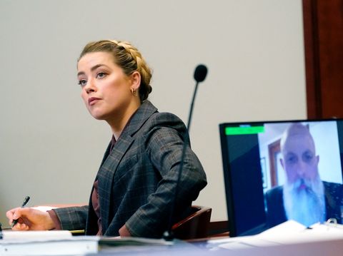 US actress Amber Heard (L) listens as Travis McGivern, security for Johnny Depp, is seen on a monitor as he testifies remotely (R) in the courtroom at the Fairfax County Circuit Court in Fairfax, Virginia, on May 2, 2022. US actor Johnny Depp sued his ex-wife Amber Heard for libel in Fairfax County Circuit Court after she wrote an op-ed piece in The Washington Post in 2018 referring to herself as a 