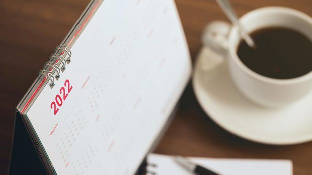 Happy new year 2022 concept.Close up Calendar 2022 schedule with cup of coffee and blank note for to do list on wooden desk.Starting the new year and planning for the future