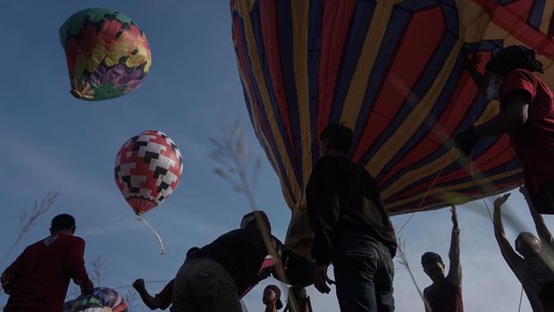 Sejumlah warga menerbangkan balon udara yang ditambatkan di tanah saat 