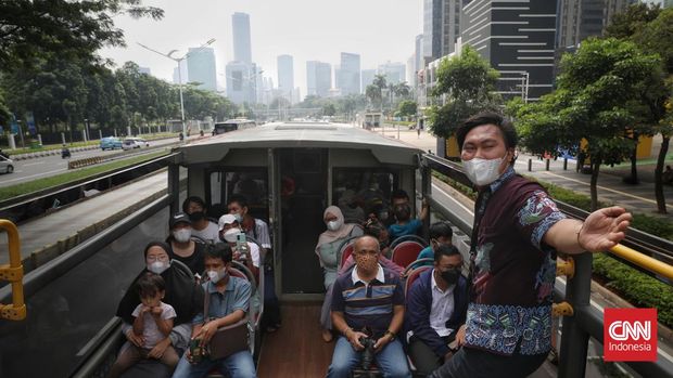 Warga menikmati suasana kota dari atas bus wisata terbuka di Jakarta, Selasa, 10 Mei 2022. PT Transportasi Jakarta (Transjakarta) memperpanjang layanan bus wisata gratis hingga Rabu (11/5/2022), dari jadwal sebelumnya pada Minggu (8/5/2022). CNN Indonesia/Safir Makki