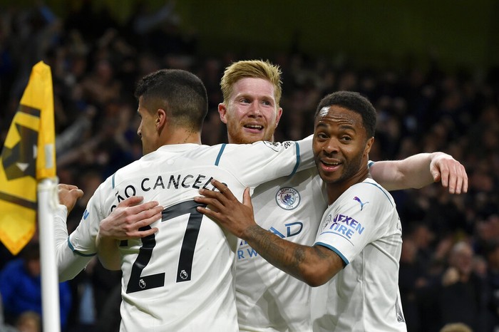 Manchester City's Kevin De Bruyne, center, celebrates with Joao Cancelo and Raheem Sterling, right, after scoring his fourth goal during the English Premier League soccer match between Wolverhampton Wanderers and Manchester City at Molineux stadium in Wolverhampton, England, Wednesday, May 11, 2022. (AP Photo/Rui Vieira)