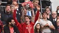 Kostas Tsimikas pun berhak mengangkat trofi Piala FA bersama skuad Liverpool. (Foto: AFP via Getty Images/BEN STANSALL)