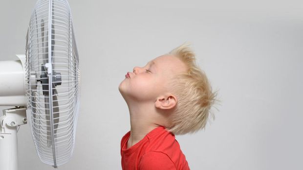 Pretty smiling blond boy in red shirt and closed eyes enjoying the cool air. Summer concept