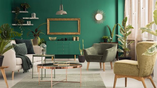 Copper table on rug between beige sofa and armchair in green spacious living room interior with mockup