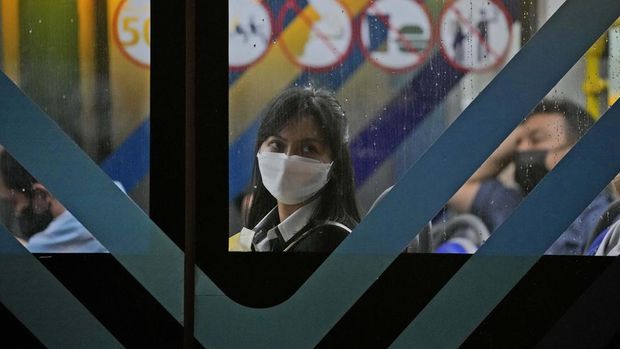 A woman wearing a mask to curb the spread of coronavirus sits inside a bus in Jakarta, Indonesia, Tuesday, May 17, 2022. Indonesia will lift its outdoor mask mandate because its COVID-19 outbreak appears to be waning, President Joko Widodo said Tuesday. (AP Photo/Dita Alangkara)