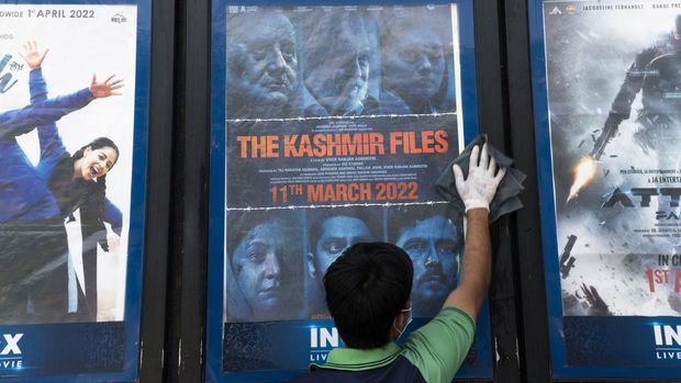 In this picture taken on April 7, 2022, a worker cleans a display with the poster of the Bollywood movie 'The Kashmir Files', outside a cinema hall in New Delhi. - Indian Hindu hardliners have jumped on an explosive new film endorsed by Prime Minister Narendra Modi on the mass flight of Hindus from Kashmir 30 years ago to stir up hatred against minority Muslims. (Photo by Xavier GALIANA / AFP) / To go with 'India-Politics-Religion-Film-History', FOCUS