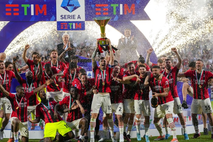 AC Milan's Alessio Romagnoli players holds up the trophy as he celebrates with teammates after winning the Italian Serie A title at the end of a match against Sassuolo, at the Citta del Tricolore stadium, in Reggio Emilia, Italy, Sunday, May 22, 2022. (AP Photo/Antonio Calanni)