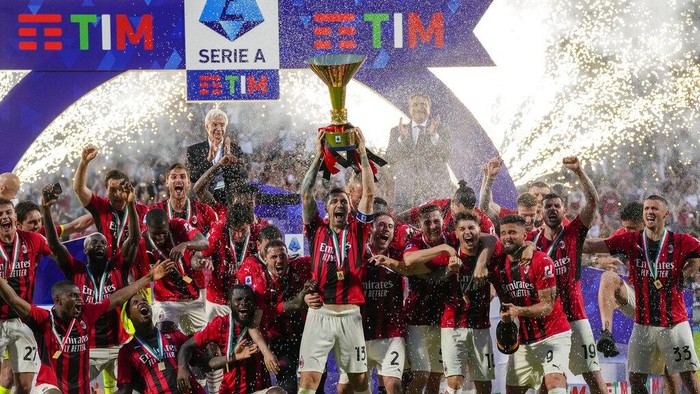 AC Milans Alessio Romagnoli players holds up the trophy as he celebrates with teammates after winning the Italian Serie A title at the end of a match against Sassuolo, at the Citta del Tricolore stadium, in Reggio Emilia, Italy, Sunday, May 22, 2022. (AP Photo/Antonio Calanni)