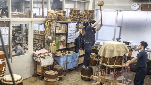 This photo taken on April 26, 2022 shows a craftspeople working on the renovation of a Japanese taiko drum at the Miyamoto Unosuke workshop in Tokyo. - Japanese taiko drumming is a musical form with roots in religious rituals, traditional theatre and the joyous abandon of seasonal festivals called matsuri. (Photo by Charly TRIBALLEAU / AFP) / TO GO WITH AFP STORY Japan-culture-music-drum-taiko, FEATURE by Sara HUSSEIN