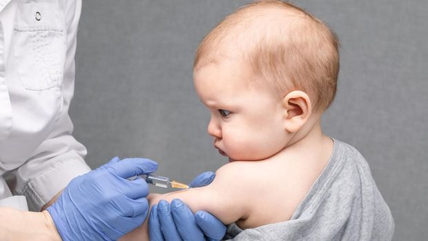 Portrait of baby girl receiving vaccination.