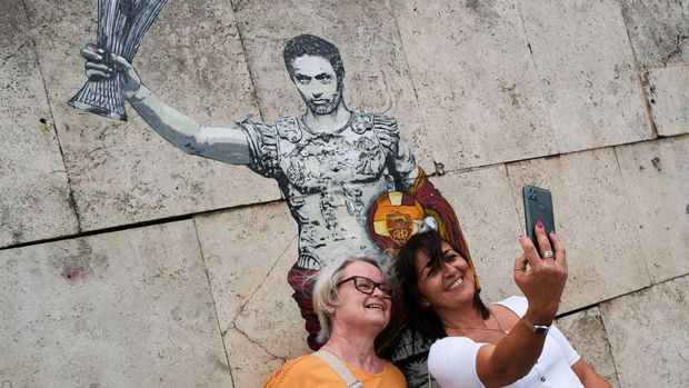 TOPSHOT - Two women take selfie in front a painting of artist Harry Greb, depicting Roma's Portuguese head coach Jose Mourinho, who led the team to the victory in UEFA Europa Conference League, in central Rome, on May 26, 2022 . - - RESTRICTED TO EDITORIAL USE - MANDATORY MENTION OF THE ARTIST UPON PUBLICATION - TO ILLUSTRATE THE EVENT AS SPECIFIED IN THE CAPTION (Photo by Andreas SOLARO / AFP) / RESTRICTED TO EDITORIAL USE - MANDATORY MENTION OF THE ARTIST UPON PUBLICATION - TO ILLUSTRATE THE EVENT AS SPECIFIED IN THE CAPTION / RESTRICTED TO EDITORIAL USE - MANDATORY MENTION OF THE ARTIST UPON PUBLICATION - TO ILLUSTRATE THE EVENT AS SPECIFIED IN THE CAPTION (Photo by ANDREAS SOLARO/AFP via Getty Images)