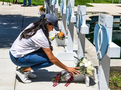 Britain's Meghan, Duchess of Sussex, places flowers as she mourns at a makeshift memorial outside Uvalde County Courthouse in Uvalde, Texas, on May 26, 2022. - Grief at the massacre of 19 children at the elementary school in Texas spilled into confrontation on May 25, as angry questions mounted over gun control -- and whether this latest tragedy could have been prevented. The tight-knit Latino community of Uvalde on May 24 became the site of the worst school shooting in a decade, committed by a disturbed 18-year-old armed with a legally bought assault rifle. (Photo by CHANDAN KHANNA / AFP)