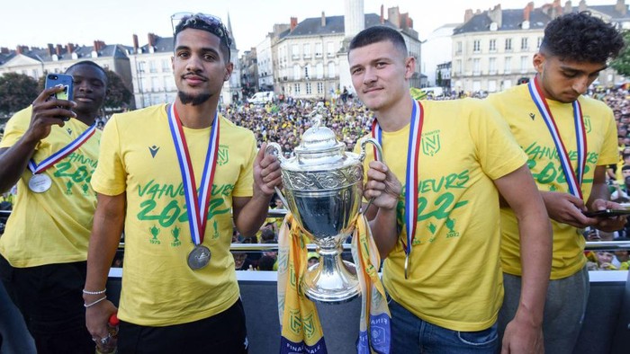 Nantes' French midfielder Ludovic Blas (L) and Nantes' French forward Quentin Merlin (R) celebrate with the trophy aboard an open-top bus during the French Cup trophy presentation on Marechal Foch Square in Nantes, western France on May 8, 2022, a day after winning the French Cup final football against OGC Nice. (Photo by Sebastien SALOM-GOMIS / AFP) (Photo by SEBASTIEN SALOM-GOMIS/AFP via Getty Images)