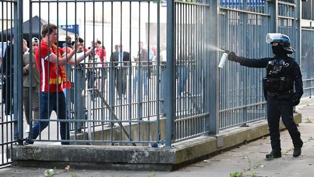 PARIS, FRANCE - MAY 28: Police spray tear gas at Liverpool fans outside the stadium as they queue prior to the UEFA Champions League final match between Liverpool FC and Real Madrid at Stade de France on May 28, 2022 in Paris, France. (Photo by Matthias Hangst/Getty Images)