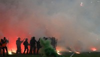 Suporter juga bikin membuat lapangan merah membara lewat lemparan-lemparan flare alias petasan suar. . Foto: AFP via Getty Images/JEAN-PHILIPPE KSIAZEK