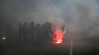 BBC menyebut flare ini dilemparkan fans ke arah tribune dan bahkan terowongan pemain. Polisi anti huru-hara pun turun tangan. Foto: AFP via Getty Images/JEAN-PHILIPPE KSIAZEK