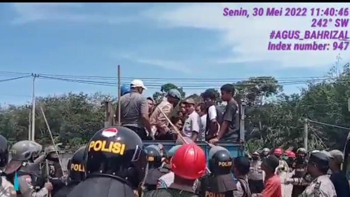 Polisi berbaret biru saat membanting seorang pria dari bak truk di Rokan Hulu, Riau.
