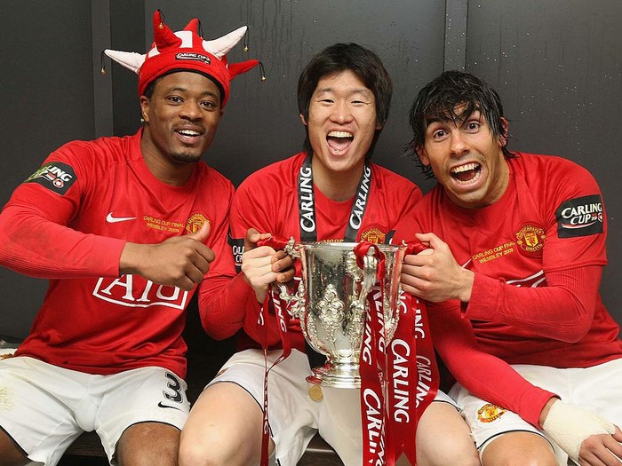 LONDON, ENGLAND - MARCH 1:  (MINIMUM USAGE FEE APPLIES - 250 GBP OR LOCAL EQUIVALENT) Patrice Evra, Ji-Sung Park and Carlos Tevez of Manchester United pose in the dressing room with the Carling Cup trophy after the Carling Cup Final match between Manchester United and Tottenham Hotspur at Wembley Stadium on March 1 2009 in London, England. (Photo by John Peters/Manchester United via Getty Images)