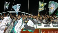 Aksi suporter mengibarkan bendera-bendera dan bernyanyi yel-yel penyemangat sepanjang pertandingan. 