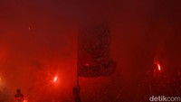 Seorang suporter mengibarkan bendera Persija Jakarta.