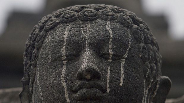 A stone figure of buddha at the ancient Borobudur temple in Central Java is smeared with volcanic ash on February 14, 2014 following the eruption of Mount Kelud volcano. Two people have been crushed to death after a volcanic eruption blanketed rooftops with rocks and ash, causing homes to cave in, an official said on February 14. Borobudur a UNESCO World Heritage Site built between 8th and 9th century is located about 200 kilometers west of Kelud volcano.  AFP PHOTO / SURYO WIBOWO (Photo by SURYO WIBOWO / AFP)