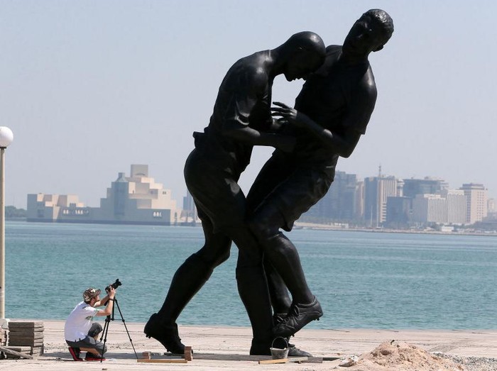 A photographer takes pictures of a bronze sculpture by French Algerian born artist Adel Abdessemed during its installation on October 4, 2013 on the Corniche in Doha after it was bought by the Qatar Museums Authority. The statue, titled 