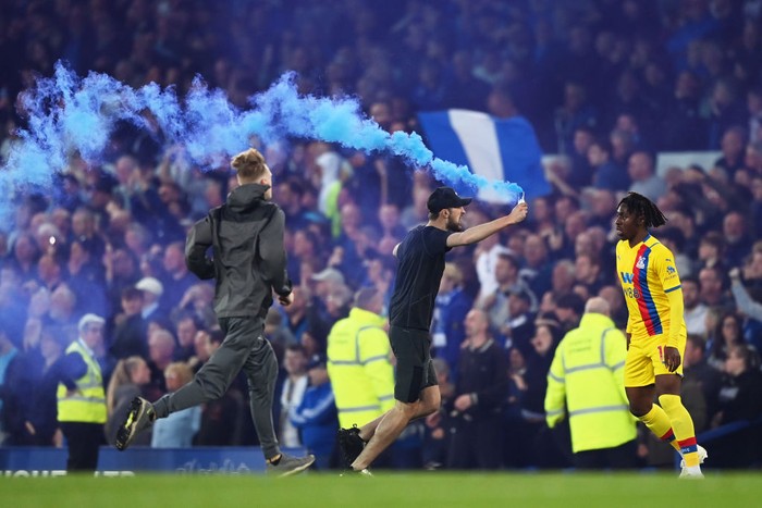 LIVERPOOL, ENGLAND - MAY 19: An Everton fan pitch invades the pitch holding a flare during the Premier League match between Everton and Crystal Palace at Goodison Park on May 19, 2022 in Liverpool, England. (Photo by Gareth Copley/Getty Images)