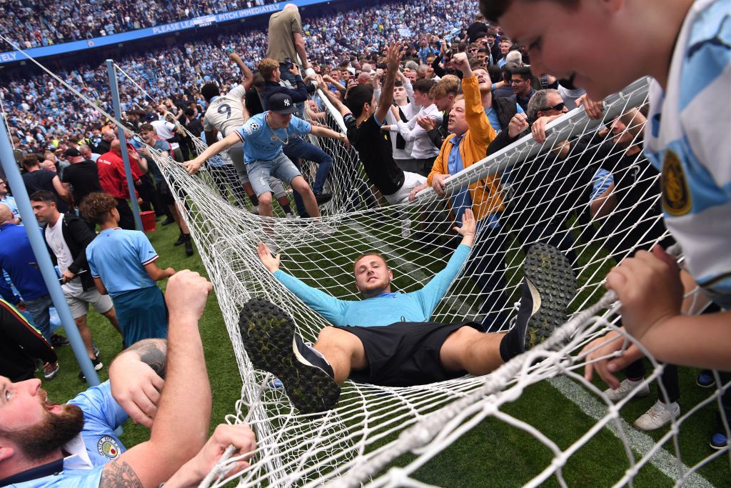 MANCHESTER, ENGLAND - MAY 22: Manchester City fans celebrate winning the Premier League title on the pitch by  climbing onto the roof of the net as the crossbar snaps after the Premier League match between Manchester City and Aston Villa at Etihad Stadium on May 22, 2022 in Manchester, England. (Photo by Stu Forster/Getty Images)