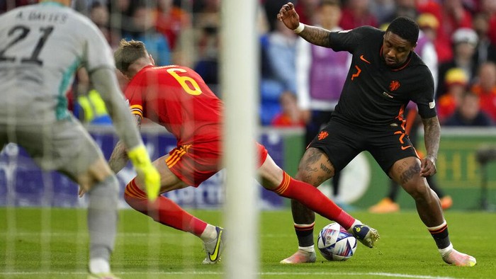 Kemenangan Dramatis Belanda Atas Wales Wales's Rhys Norrington-Davies, front, duels for the ball with Netherlands' Hans Hateboer during the UEFA Nations League soccer match between Wales and the Netherlands at Cardiff City Stadium, in Cardiff, Wales, Wednesday, June 8, 2022. (AP Photo/Matt Dunham )