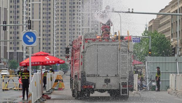 A worker carries out disinfection on top of a fire engine, in an area under lockdown amid the coronavirus disease (COVID-19) outbreak, in Chaoyang district of Beijing, China May 23, 2022. REUTERS/Thomas Suen