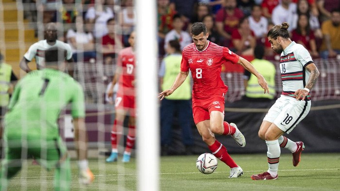 Ronaldo Nggak Main, Portugal Takluk dari Swiss Portugal's midfielder Bruno Fernandes, center, fights for the ball with Switzerland's defender Ricardo Rodriguez, left, and Switzerland's defender Nico Elvedi, right, during the UEFA Nations League group A2 soccer match between Switzerland and Portugal at the Stade de Geneve stadium, in Geneva, Switzerland, Sunday, June 12, 2022. (Jean-Christophe Bott/Keystone via AP)