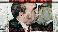 Mural itu mengadopsi karya populer Dmitri Vrubel, yang melukis ‘My God, Help Me to Survive This Deadly Love’ di Tembok Berlin pada 1990. Vrubel melukis ulang potret dua pejabat komunis Soviet dan Jerman Timur, Leonid Brezhnev dan Erich Honecker sedang berciuman. (Foto: picture alliance via Getty Image/picture alliance)