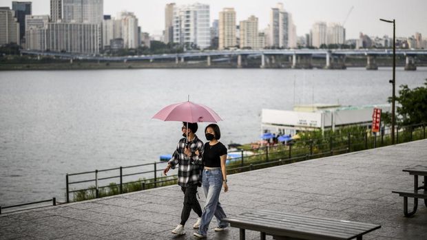 A couple share an umbrella as they walk along the Han River during a light rain shower in Seoul on June 10, 2022. (Photo by Anthony WALLACE / AFP)