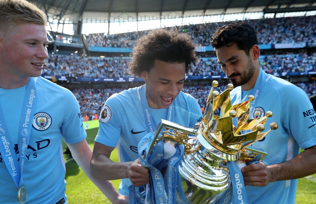 MANCHESTER, ENGLAND - MAY 06: Kevin De Bruyne of Manchester City, Leroy Sane of Manchester City and Ilkay Gundogan of Manchester City celebrate with the trophy after the Premier League match between Manchester City and Huddersfield Town at Etihad Stadium on May 6, 2018 in Manchester, England.  (Photo by Victoria Haydn/Manchester City FC via Getty Images)